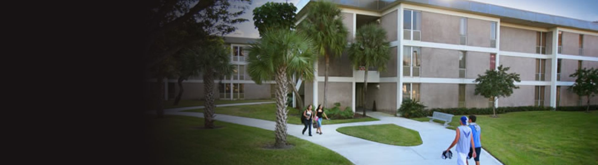 Students walk to and from the FFV residence halls on sidewalks cutting through well-groomed lawns with palms lining the building and paths.