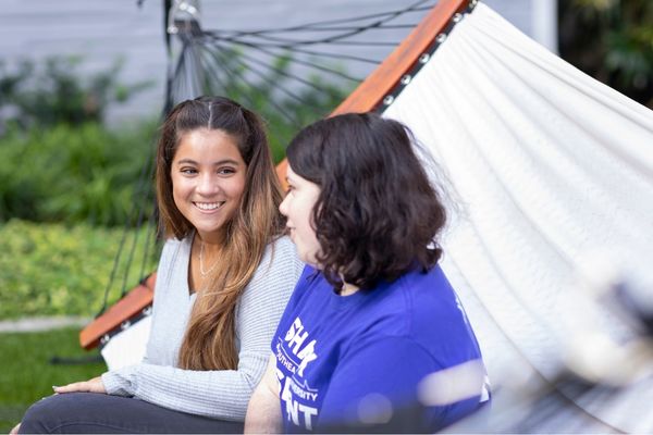 Two smiling NSU students sitting on a hammock. 